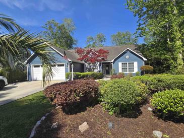 Charming blue home boasts an inviting entrance framed by lush landscaping, stone accents and a manicured lawn at 2333 Brick Dr., Longs, SC 29568