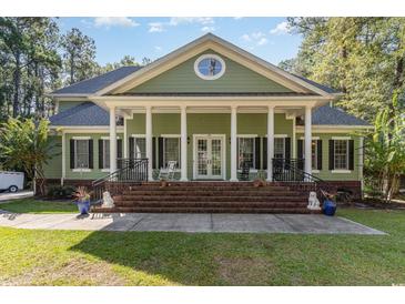 Charming home featuring a large front porch with stately columns and beautiful brick stairs and landscaped front yard at 487 Lantana Circle, Georgetown, SC 29440
