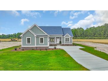 Charming craftsman-style home with blue siding, landscaped yard, and a paved driveway at 604 Highway 747, Loris, SC 29569