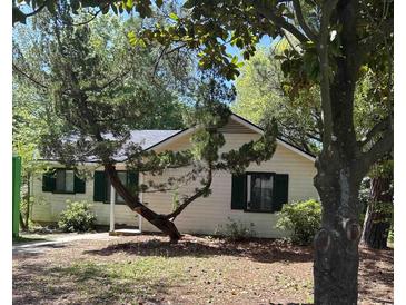 Charming single-story home with white siding, green shutters, and mature trees in a peaceful setting at 8 Ryan Ln., Myrtle Beach, SC 29579