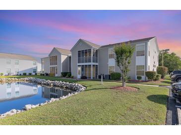 Beautiful condominium exterior featuring a serene pond and well-maintained landscaping at 8796 Cloister Dr. # B, Surfside Beach, SC 29575