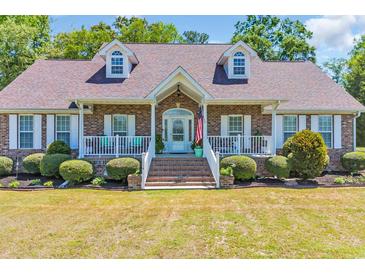 Charming brick home featuring dormer windows, white trim, a welcoming front porch and landscaped yard at 1014 Academy Dr., Conway, SC 29526