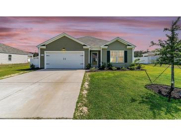 Charming single-story home featuring a well-manicured lawn, attached garage, and welcoming front entrance at 211 Seasons Trace Loop, Longs, SC 29568