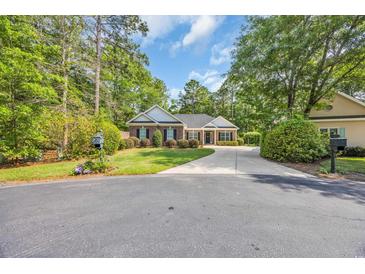 Charming brick home featuring a circular driveway and well-manicured lawn and mature trees at 455 Dornoch Dr., Pawleys Island, SC 29585