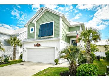 Charming two-story green home featuring a front-facing garage and meticulously landscaped yard with palm trees at 512 Chanted Dr., Murrells Inlet, SC 29576