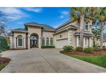 Stunning home featuring a symmetrical elevation, arched windows and entrance, attached garage, palm trees, and a spacious driveway at 9060 Abingdon Dr., Myrtle Beach, SC 29579