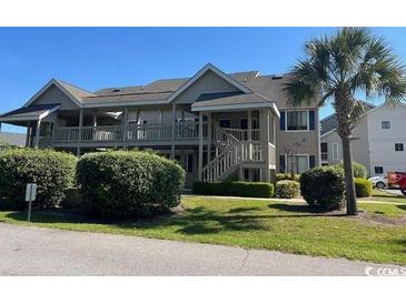 Charming condo with palm trees, well-kept landscaping, and inviting walkways to upper-level entrances at 1870 Auburn Ln. # 21 E, Surfside Beach, SC 29575