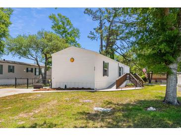 Charming white mobile home featuring a well-maintained lawn and inviting wood porch with stairs at 2706 Willow St., North Myrtle Beach, SC 29582