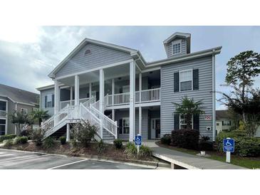 Attractive condo building with covered porches, white railings and stairs, gray siding, and manicured landscaping at 307 Black Oak Ln. # 102, Murrells Inlet, SC 29576