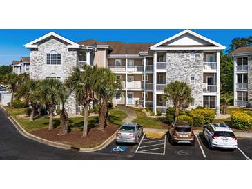 Three-story condo building features brick facade, white trim, balconies, and palm tree landscaping with parking at 4749 Wild Iris Dr. # 205, Myrtle Beach, SC 29577