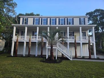 Stunning two-story home with a spacious porch, palm trees, and a well-maintained lawn at 507 Hillside Dr. N, North Myrtle Beach, SC 29582