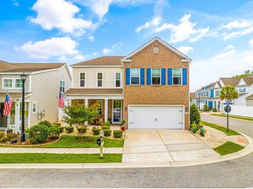 Charming two-story home boasts a brick facade, blue shutters, a well-manicured lawn, and an attached two-car garage at 700 Lorenzo Dr., North Myrtle Beach, SC 29582
