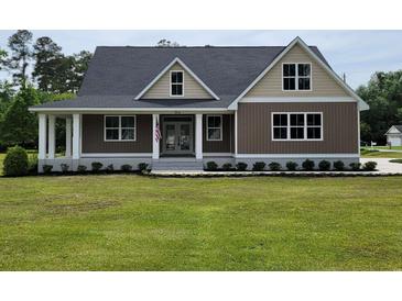 Charming home featuring an inviting front porch and lush green lawn with manicured landscaping at 214 Carolina Dr., Loris, SC 29569