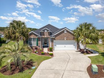 Charming brick home with a two-car garage, manicured landscaping, and palm trees at 2940 Tigers Eye Rd., Little River, SC 29566