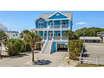 Charming blue beach house with double balconies and white stairs, surrounded by lush landscaping at 4206 S Ocean Blvd., North Myrtle Beach, SC 29582