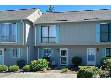 Inviting townhouse exterior with light gray facade and blue shutters, showcasing well-maintained landscaping at 913 Villa Dr. # 913, North Myrtle Beach, SC 29582