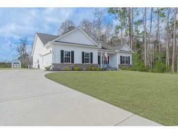 Charming white home featuring a well-manicured lawn, a concrete driveway, and classic black shutters at 250 Ole Maple St., Loris, SC 29569