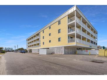 Beautiful exterior shot of a yellow condo building with large balconies under a bright blue sky at 301 N Waccamaw Dr. # 110, Murrells Inlet, SC 29576