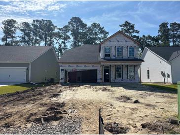 New construction home with a two-car garage surrounded by dirt and other homes in the distance at 402 Sun Colony Blvd., Longs, SC 29568