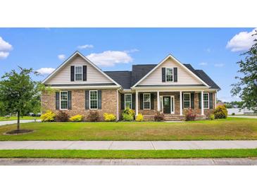 Charming brick home with manicured lawn, lush landscaping, and inviting front porch at 4067 Ridgewood Dr., Conway, SC 29526
