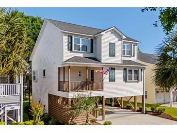 Charming coastal home on stilts with a covered porch and an American flag waving proudly at 527 Bay Drive Ext., Garden City Beach, SC 29576