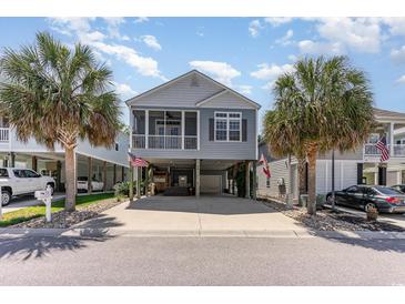 Charming coastal home featuring a screened porch, neutral siding, palm trees, and ample parking beneath at 708 Ashland Ave., North Myrtle Beach, SC 29582