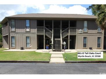 Inviting condo with two-story facade, accessed by a central staircase and featuring wood-look siding and verdant lawn at 861 Tall Oaks Ct. # D-61, Myrtle Beach, SC 29588