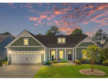 Charming home with a two-car garage, a well-manicured lawn and cozy front porch under a colorful sky at 9169 Nw Oldfield Rd., Calabash, NC 28467