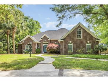 Charming brick home featuring a lush, landscaped yard and inviting walkway at 1203 Crooked Oak Dr., Pawleys Island, SC 29585