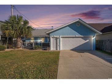 Charming blue house featuring an attached garage, green lawn, and palm tree at 1415 Edge Dr., North Myrtle Beach, SC 29582