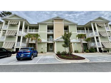 Inviting exterior view of a charming two-story condo building with palm trees and well-maintained landscaping at 144 Puffin Dr. # 1-A, Pawleys Island, SC 29585