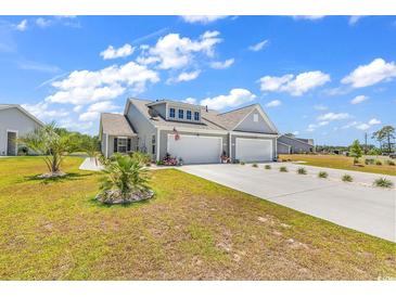 Charming home featuring a two-car garage, well-manicured lawn and lush landscaping with palm trees at 528 Courtridge Loop, Conway, SC 29526