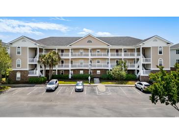 Charming condo complex with multiple stories, white balconies, well-maintained landscaping and convenient parking spaces at 5751 Oyster Catcher Dr. # 334, North Myrtle Beach, SC 29582