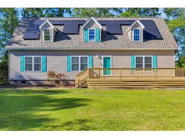 Charming home featuring solar panels, a large deck, and teal shutters, enhancing its curb appeal at 6357 Highway 707, Myrtle Beach, SC 29588