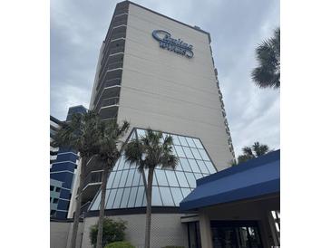 Exterior shot of the building with palm trees and blue Carolina Winds signage against a cloudy sky at 200 76Th Ave. N # 608, Myrtle Beach, SC 29572
