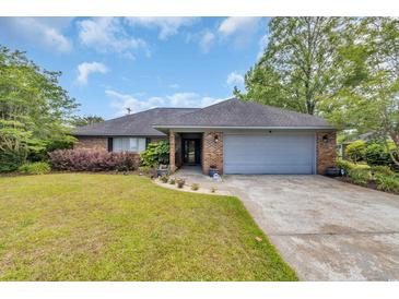 Charming brick home boasts a manicured lawn, mature trees, and an attached two-car garage at 215 Lander Dr., Conway, SC 29526