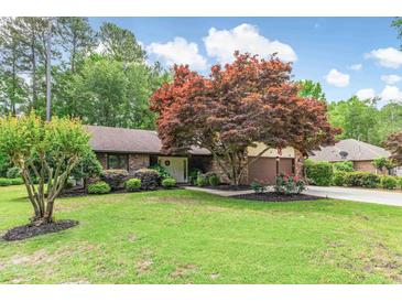 Charming brick home featuring a well-manicured lawn and beautiful landscaping, including a vibrant Japanese maple at 33 Brassie Dr., Carolina Shores, NC 28467