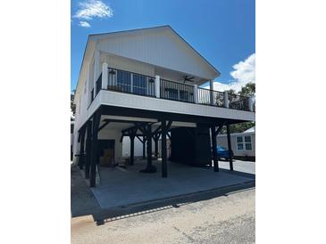 A beautiful white elevated two-story home with a black iron balcony, sturdy stilts, and ample covered parking at 6001 - 1766 S Kings Hwy., Myrtle Beach, SC 29575