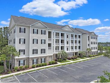 Beautiful condominium complex showcasing light siding, black shutters, large parking area, and manicured landscaping at 719 Shearwater Ct. # 301, Murrells Inlet, SC 29576