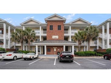 Attractive condo building featuring palm trees, a brick facade, and covered balconies with white railings at 1000 Ray Costin Way # 107, Garden City Beach, SC 29576