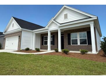 Inviting brick and vinyl sided home featuring a charming front porch with white columns and well-manicured lawn at 1033 Jase Dr., Longs, SC 29568