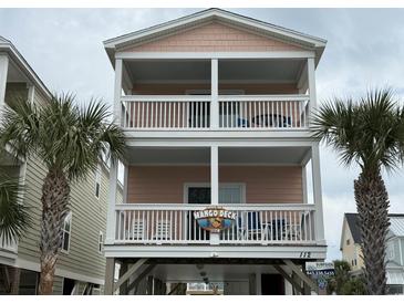 Charming coastal home featuring double balconies, white railings, and palm trees at 112 B 12Th Ave. N, Surfside Beach, SC 29575
