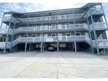 Attractive three story building with ample covered parking and stairs leading up to covered walkways in front of each unit at 116 S Waccamaw Dr. # 205, Murrells Inlet, SC 29576