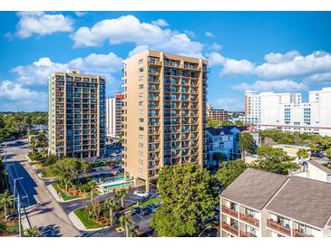 An aerial view showcasing the condo complex, featuring palm trees, a pool, and nearby roads on a sunny day at 210 75Th Ave N # 4042, Myrtle Beach, SC 29572