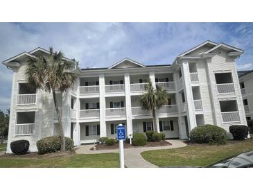 Charming condo building featuring multiple balconies, a manicured lawn, and beautiful palm trees for a tropical feel at 493 White River Dr. # 28C, Myrtle Beach, SC 29579