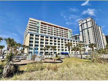 Large modern condo building featuring multiple balconies with palm trees and playground at 5300 N Ocean Blvd. # 1102, Myrtle Beach, SC 29577