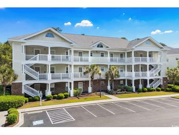 Three-story condo building with white railings, palm trees, and a parking lot at 6015 Catalina Dr. # 332, North Myrtle Beach, SC 29582
