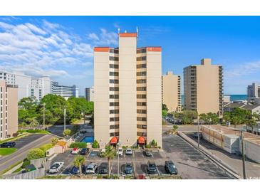 High-rise condo building showing parking, pool, and landscaping on a bright, sunny day at 7509 N Ocean Blvd. # 404, Myrtle Beach, SC 29572