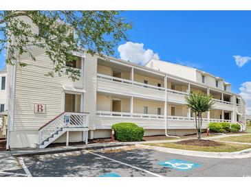 Charming condo building with multiple floors, exterior corridors, and manicured landscaping under a blue sky at 1100 Possum Trot Rd. # B102, North Myrtle Beach, SC 29582