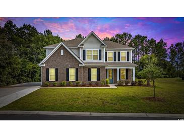 Beautiful two-story home featuring a brick facade, black shutters, lush lawn, and mature trees under a colorful dusk sky at 1303 Bermuda Grass Dr., Myrtle Beach, SC 29579